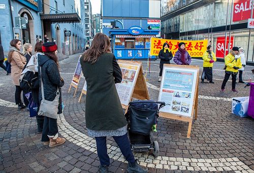 '图1~2:在斯德哥尔摩繁华的闹市区(Hötorget)法轮功学员举办弘法讲真相活动,民众观看真相展板,了解真相。'