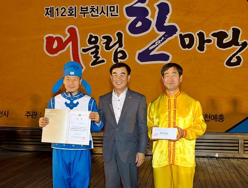 '图6:韩国京畿道议会文化观光委员长(中)给参加本次庆典活动获一等奖——最优秀奖的法轮功团体颁奖。'