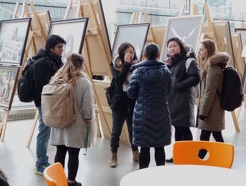 图7:观看画展的阿伯达大学学生认真听法轮功学员介绍法轮功真相。