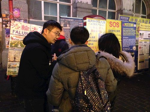 '图2:二零一七年中国新年期间,一对华人青年在伦敦唐人街向法轮功学员了解真相并选择三退'