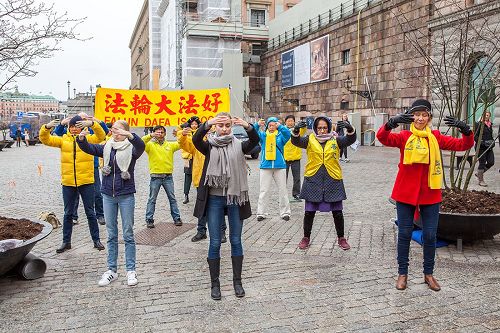 '图1:瑞典法轮功学员在斯德哥尔摩最热闹的皇宫旁的钱币广场举办法轮大法信息日活动。图为法轮功学员正在演示第二套功法——法轮桩法。'