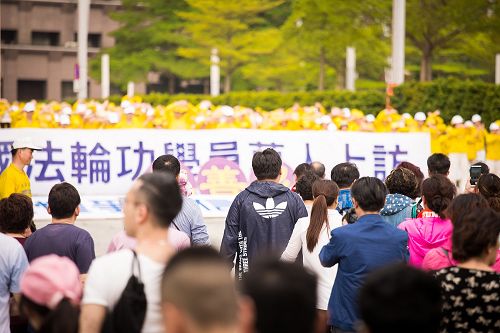 图6-7:法轮功学员在台北市政府前的市民广场举行纪念四二五活动。经过的大陆游客、市民驻足观看,并拿起手机拍照。