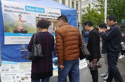 '图5:中国游客看展板了解真实的法轮功,并拍照留念'