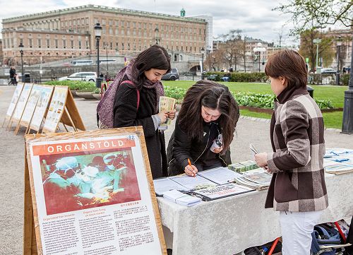 了解真相后的人们在反活摘器官的签名册上签名,支持法轮功学员反迫害。