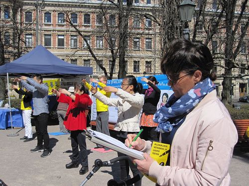 '图2:法轮功学员正在向民众展示法轮功功法,分享法轮大法的美好。'