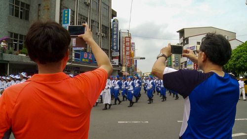 '图4:很多市民拿手机争相对着行进中的天国乐团拍照。'