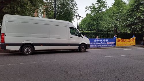 '图2:爱尔兰中使馆调遣车辆遮挡法轮功学员横幅,后被警方要求立即离开'