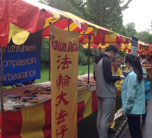 '图1~3:细雨中学员们给游人讲真相,很多人驻足了解法轮功'
