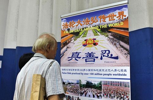 '图3:这位民众真正仔细观看大法弘传世界的真相横幅。'