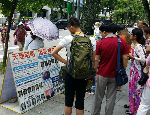 '图1~2:国父纪念馆外,大陆游客认真阅读法轮功真相展板'