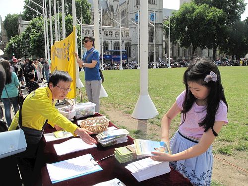 '图4:二零一七年七月十八日,小法童(右一)和爸爸一起参加在英国议会大厦前参加法轮功学员讲真相反迫害活动'