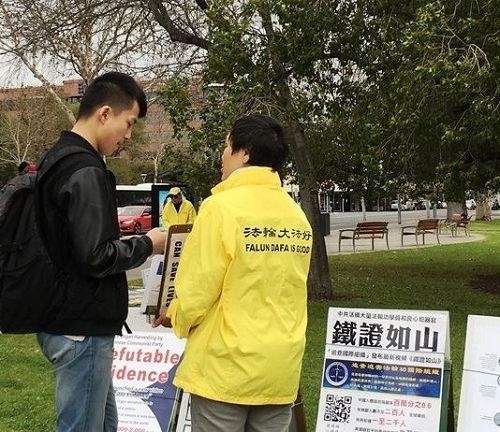 '图5:来自中国大陆的年轻人,在真相展板前驻足良久,聆听法轮功学员讲述真相,最后欣然用化名退出了中共的团、队组织。'