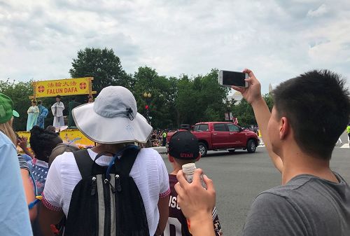 '图7:大陆游客用手机拍下在中国见不到的法轮功学员游行场面。'