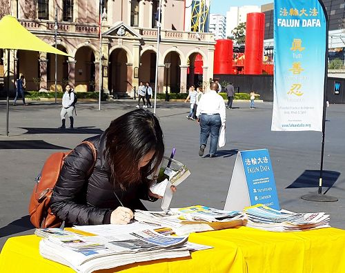 '图6:杰西卡(Jessica Jenguyen)径直走到签名支持反迫害摊位上签名'