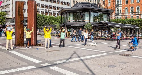 '图1:在瑞典文化节期间,法轮功学员在斯德哥尔摩的北城广场(Normalmstorget)设立真相点向民众介绍法轮大法的真相。图为学员们正在展示法轮功的第二套功法——法轮桩法。'