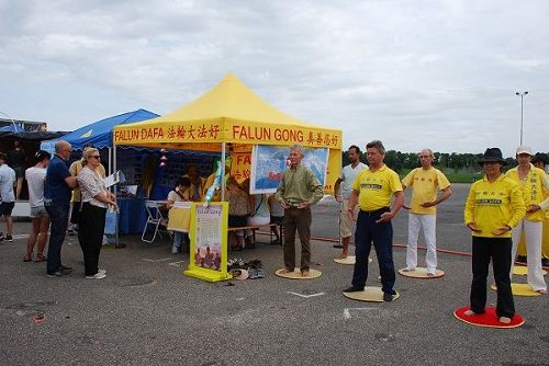'图4:法轮功学员们在展位旁全天展示功法,吸引游客驻足观看。'