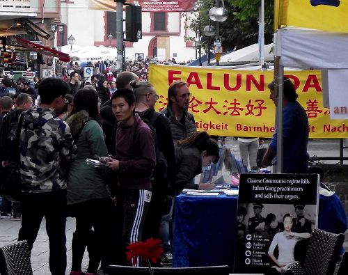 '图2:法轮功的展台前人流穿梭不息,他们拿走资料,在反迫害的表上签名'