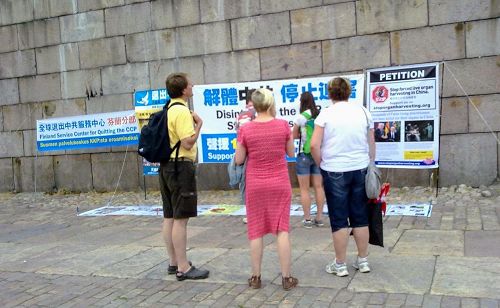'图2:议会广场上,游客观看横幅,了解法轮功真相'