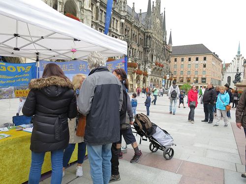 '图1~6:二零一七年九月二日,法轮功学员在德国慕尼黑的玛琳广场(Marienplatz)举办讲真相活动,不少过往民众驻足了解真相,并签名谴责中共活摘法轮功学员器官。'