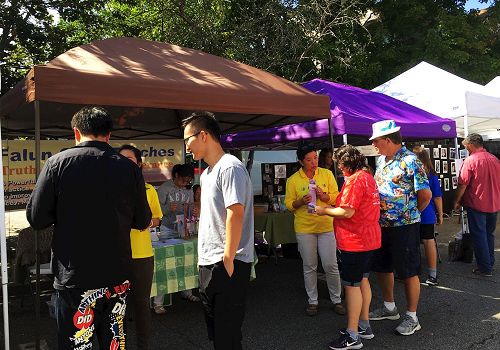 '图1~3:法轮功学员在艺术节的社区展区设了展位,向人们介绍法轮大法'