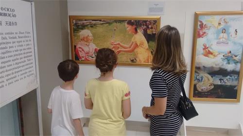 '图2:Joelma一家仨口认真欣赏真善忍美展画作'