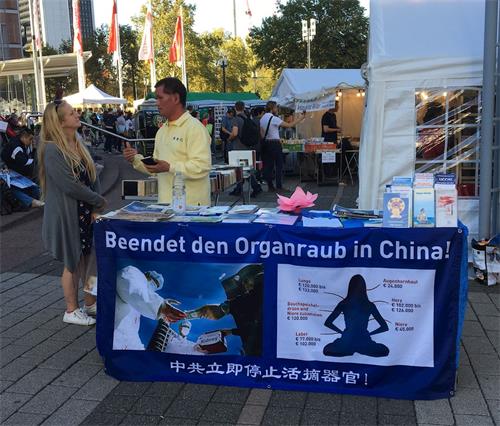 '图1~2:参观者被法轮功展位所吸引,前来了解详情。'