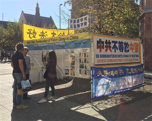 '图8:法轮功学员Volker(左二)在市中心给一对年轻人讲真相。'