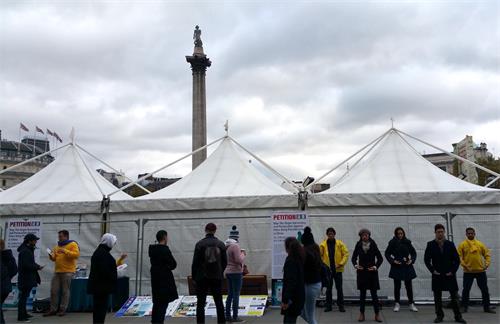 图1-2:二零一八年十月二十七日,法轮功学员在伦敦特拉法加(Trafalgar Square)广场北平台发放真相传单、炼功、讲真相、征签反迫害