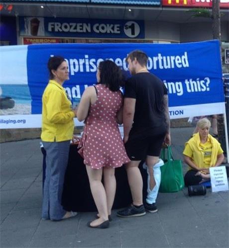 '图3:玛丽安(左)向游客介绍法轮功,讲迫害真相'