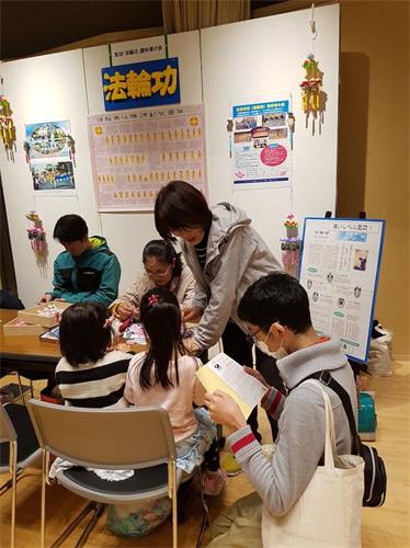 '图8:在展位前仔细阅读法轮功资料的男子'