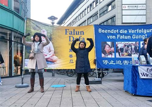 '图1:二零一八年十一月三日,法轮功学员再次来到德国汉堡火车站附近的斯碧塔勒街(Spitalerstrasse)举办信息日活动。祥和的功法演示和揭露中共血腥迫害的真相横幅形成了鲜明的对比。'