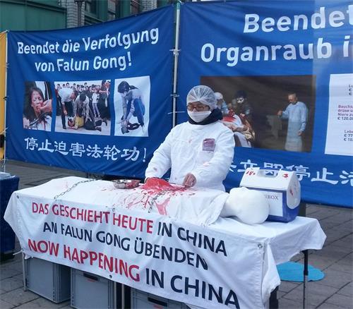 '图2:法轮功学员演示中共活摘罪行,很多路人感到震惊'