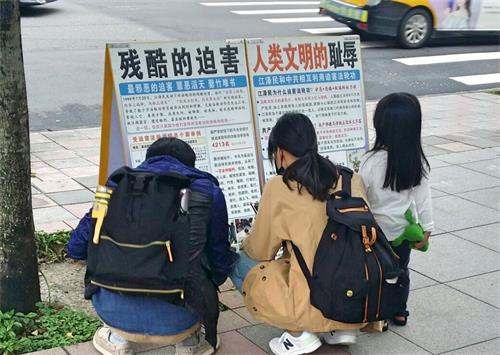 '图4:有的游客蹲下来阅读真相展板。'