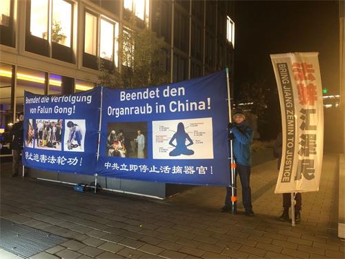 '图:二零一八年十一月二十六日晚,法轮功学员在汉堡市中心,经济峰会举办招待会的Esplanade街上,竖立起有夜间照明灯的大型彩色横幅,希望能引起人们关注正在中国发生的活摘器官罪行。'