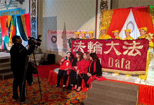 '图6:TV?Asia电视台的摄影师Madan以腰鼓队学员及“法轮大法”条幅为背景进行采访。'