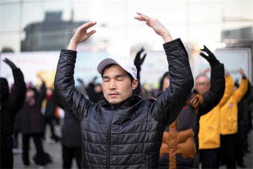 '图2:韩国法轮功学员在首尔市中心明洞中央邮局前炼法轮大法的第二套功法-法轮桩法。'