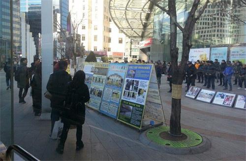 '图4:来自中国大陆的一对青年男女走近真相展板,了解法轮功真相'