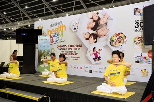 '图2~3:新加坡法轮功学员登台向参展民众展示平静祥和的五套功法'