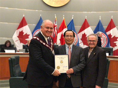 '图1:二零一八年二月十三日晚七点,加拿大万锦市市长Frank Scarpitti(左)在市议政厅向参加二零一七年圣诞游行的获奖团体颁发奖状,多伦多天国乐团获乐团类别二等奖,多伦多天国乐团团长江帆(中)领奖。'