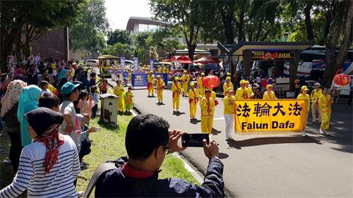 '图5:游客开心地欢迎法轮功的游行'