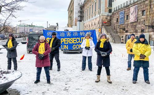 '图1:法轮功学员们冒着严寒在斯德哥尔摩市中心皇宫旁的钱币广场上举办讲真相活动。'