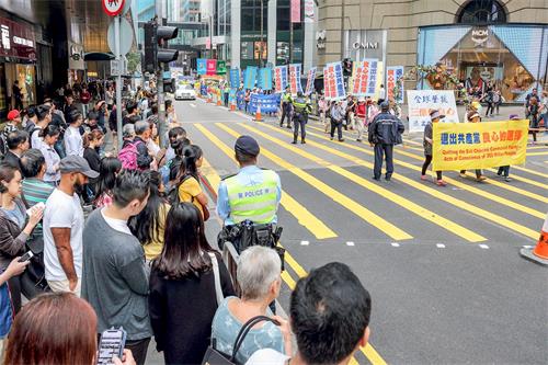 '图6~14:三月十八日下午二时,香港法轮功学员在香港市中心举行游行活动,庆祝并声援近三亿人退出中共党、团、队组织,吸引许多香港市民和大陆游客驻足观看。'