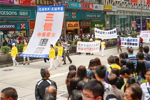 '图6~12:近千人的游行队伍在天国乐团的领头下从长沙湾游乐场出发,途经游客购物热点,吸引许多人驻足观看和手机拍摄,大陆游客亲眼看到法轮功,很震撼。'