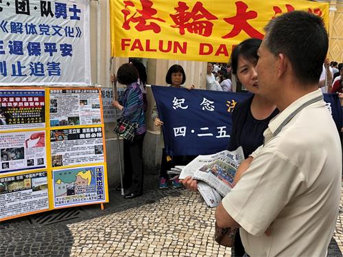 '图3:游客听法轮功学员讲真相'