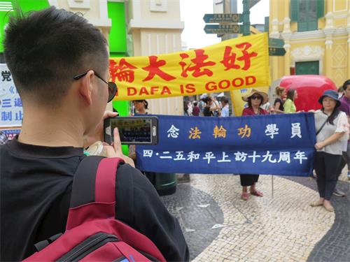 '图4:游客拍摄法轮功真相横幅留念'