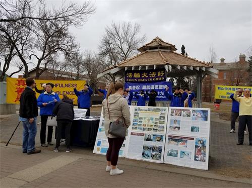 '图1:市民被法轮功学员祥和的功法吸引,开始驻足观看展板。'