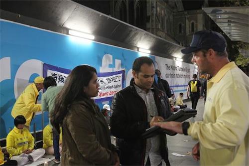 '图7~8:墨尔本学员在烛光夜悼活动中向人们讲真相'