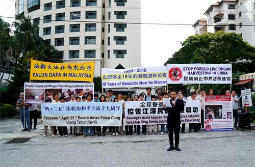 '图1:二零一八年四月二十二日,部份马来西亚法轮功学员,在中共驻马大使馆附近举行集会,纪念四二五和平上访十九周年。法轮功学员代表郭先生现场宣读马来文文告。'