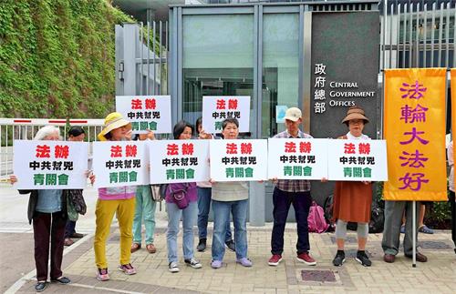 '图2:法轮功学员手持标语,要求港府法办中共帮凶青关会。'