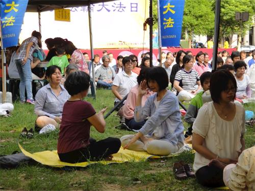 '图7~8:现场有学员义务教功,不少民众学炼法轮功。'